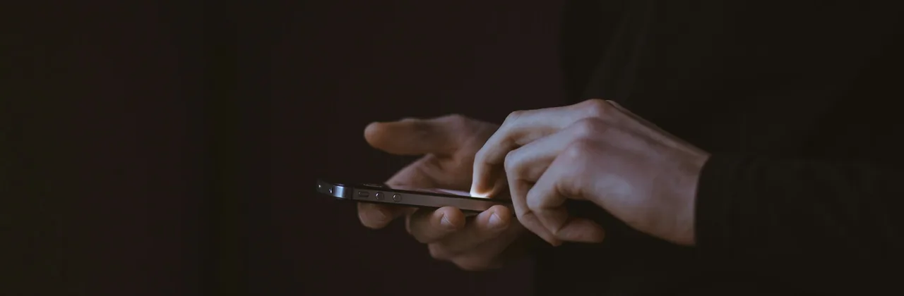 Manos usando un teléfono en la oscuridad