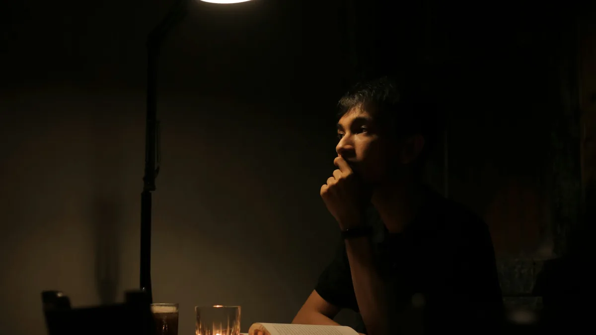 Persona leyendo concentrada bajo una lámpara de noche